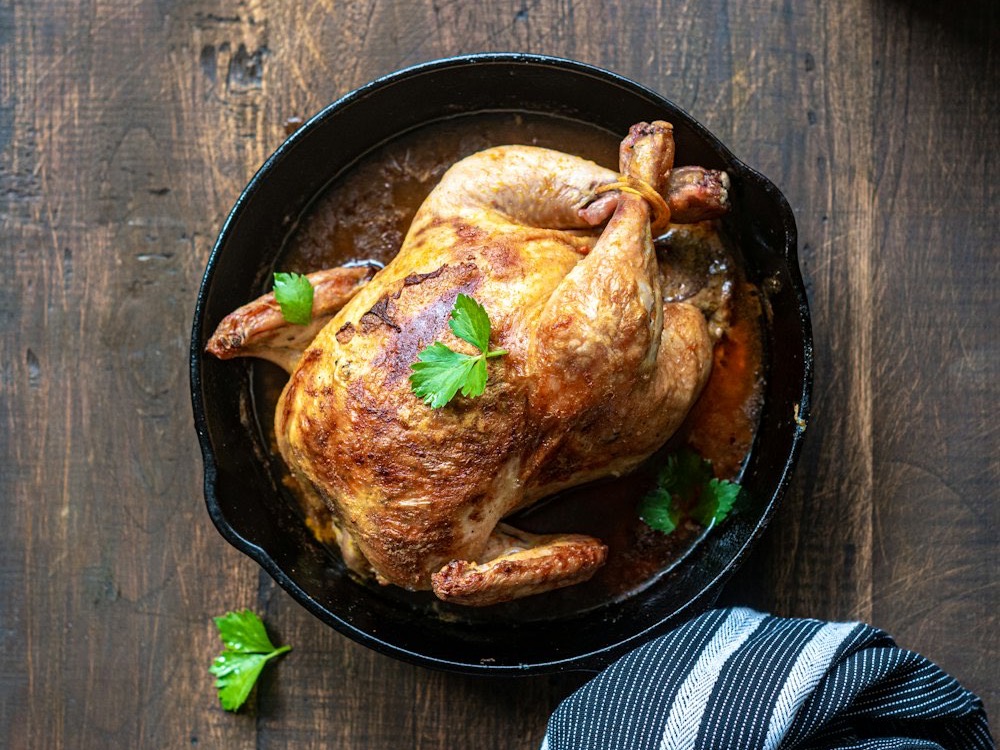 A whole roast chicken in a cast-iron skillet
